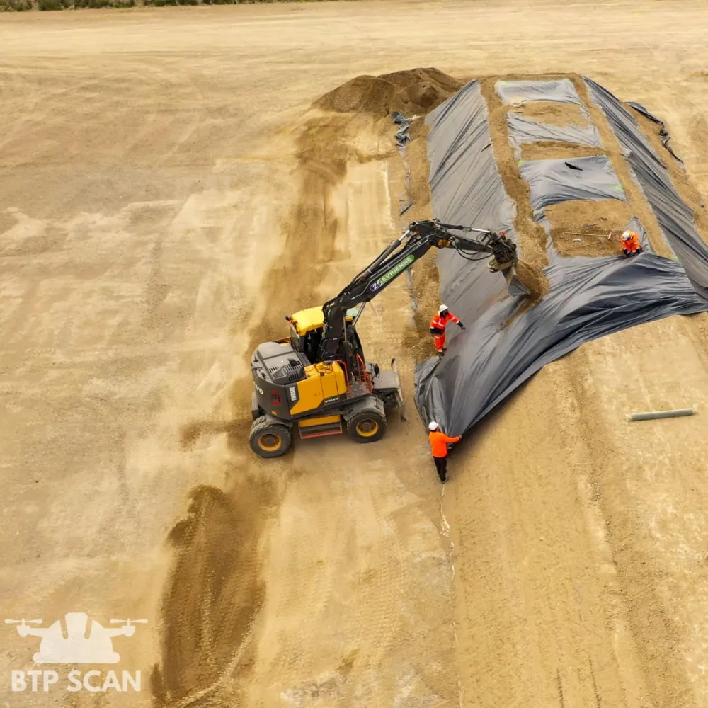 Excavatrice couvrant un dôme avec des ouvriers